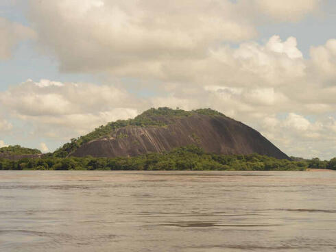 Lanscape of brown and green mountain with water in foreground