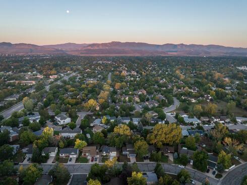 summer dawn with a full moon over residential area of Fort Collins and foothills of Rocky Mountains in northern Colorado, aerial view