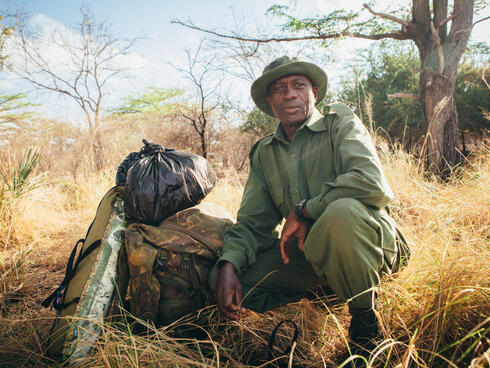 A wildlife ranger next to his kit bag and rations in Selous