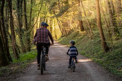 Father and son ride bikes on path through the woods
