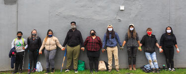Groundwork Ohio River Valley’s Green Team stands in front of a grey wall holding hands