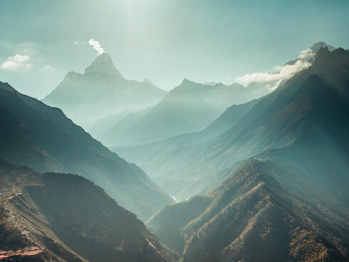 The breathtaking panoramic view the mighty misty snow-capped Himalayas and the canyons with the coniferous forests.