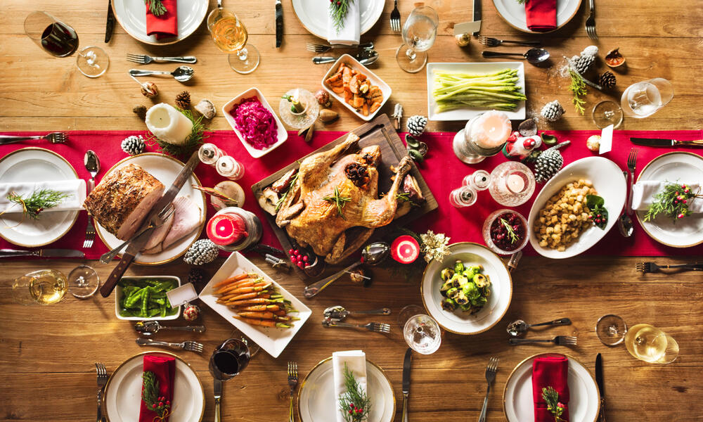 Aerial view of a festive table full of food and drinks on a red table runner