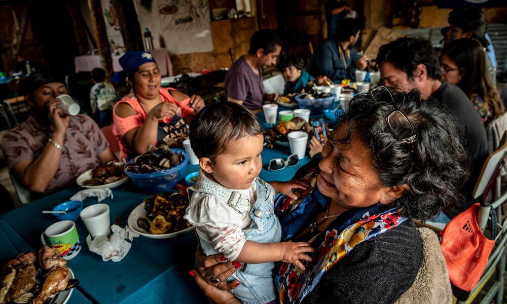 Generations of Huilliche families enjoy a curanto around a table