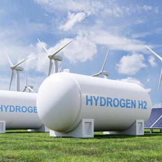 A hydrogen tank in front of solar panels and wind turbines. 