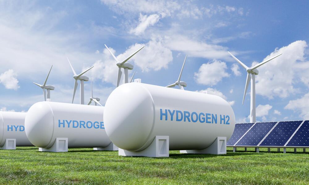 A hydrogen tank in front of solar panels and wind turbines. 