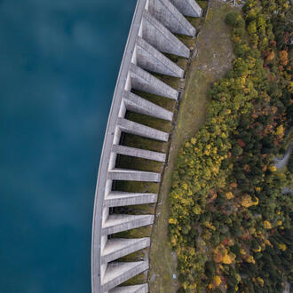 Aerial view of a hydropower dam with water on one side and forest on the other