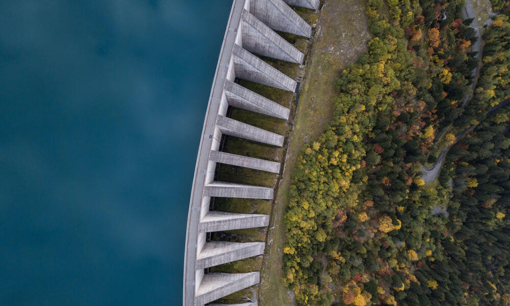 Aerial view of a hydropower dam with water on one side and forest on the other