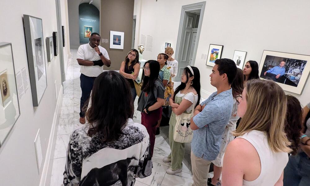 A group of BRIDGE interns gather around a photo at a museum.