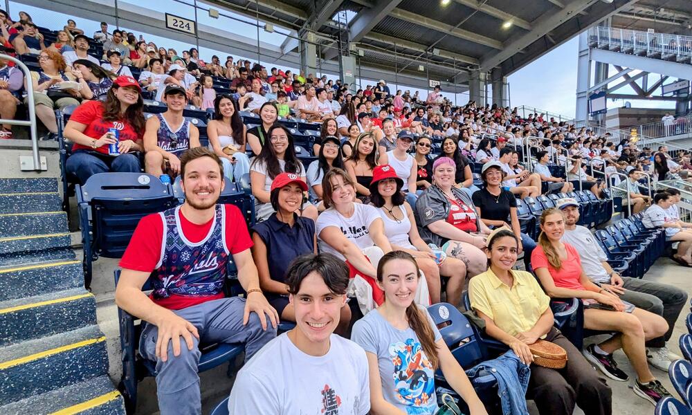 2024 BRIDGE interns sit together in a baseball stadium to watch a Nationals game