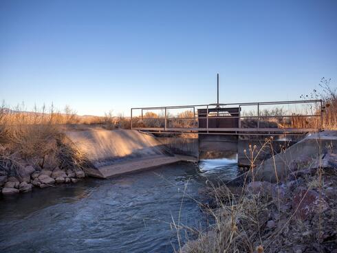 A concrete and metal structure with a small opening straddles the river