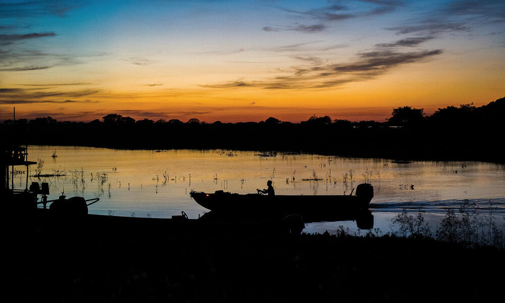 Sunset along river with canoe silhouette