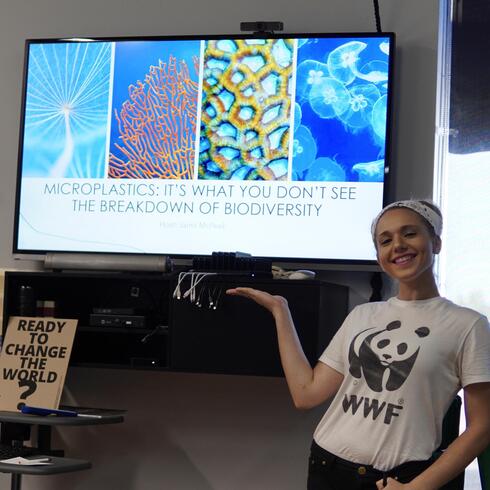 Panda Ambassador Jaimi McPeek stands in front of a screen that shows her plastics pollution presentation