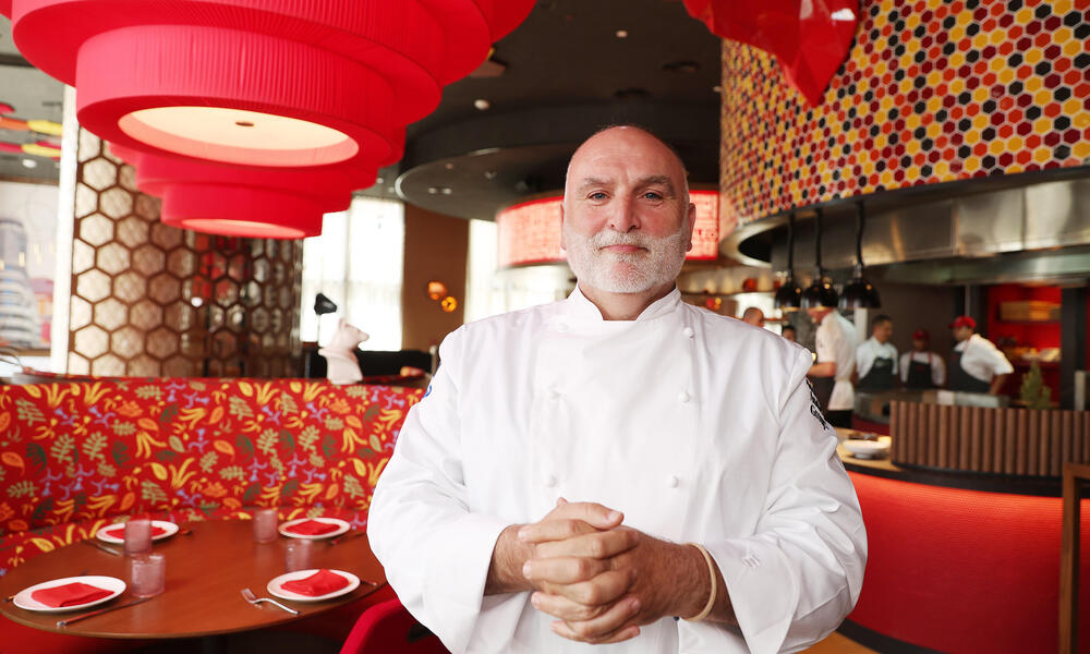 Jose Andres stands in his restaurant with his hands clasped.