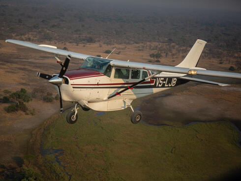 A small plane flying over African landscape