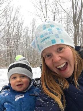 A smiling woman and baby outdoors in the snow