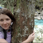 Katherine Devine hugs a tree while hiking