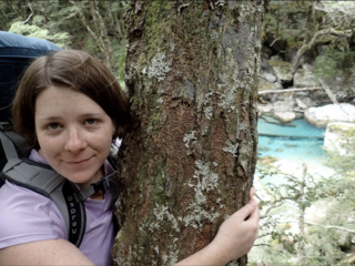 Katherine Devine hugs a tree while hiking