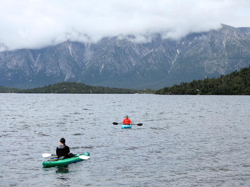 Two kayakers on the water in Lake Iliamna on a cloudy day