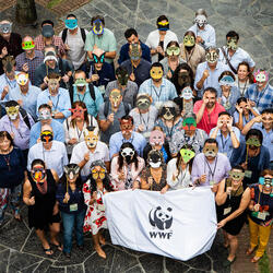 A group of people wearing  face masks representing different animals and holding a banner with a WWF logo.
