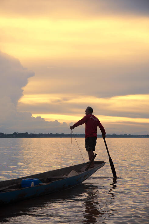 Asia fisherman net using on wooden boat casting net sunset or sunrise in  the Mekong river Stock Photo