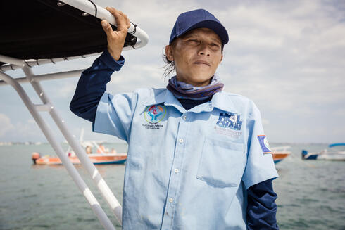 Manuel Munoz looks out onto the water while standing on a boat and wearing a hat