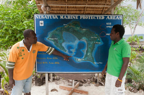 A man points to a map of marine protected islands while another man observes