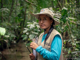 Portrait of Marisela Silva Parra standing in the forest with a clipboard