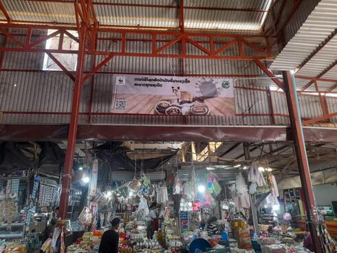 A busy market in Lao PDR with a banner on the ceiling about reducing wild meat consumptions