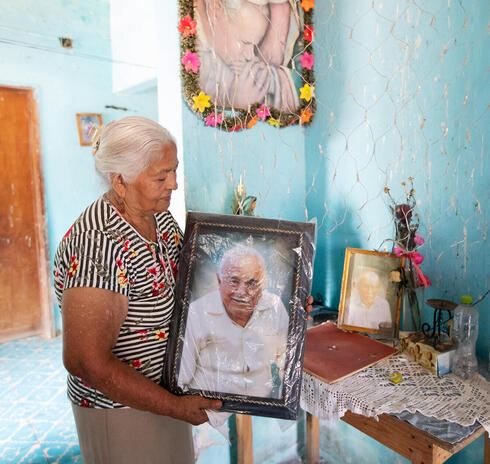 Older woman holding portrait of older man