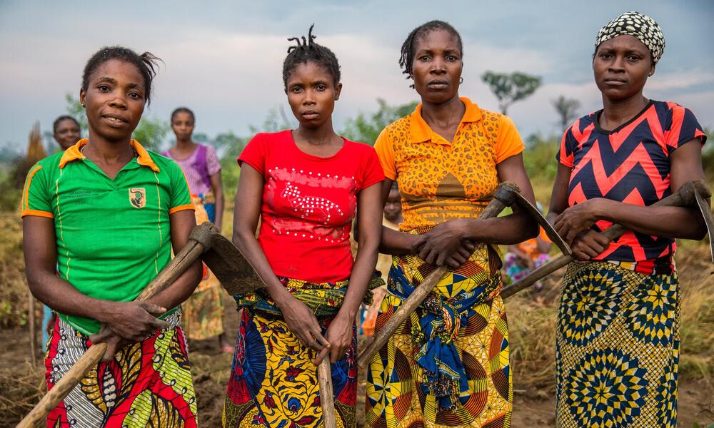 four women stand together representing the Mbanzi Women's Association. Mbanzi, Democratic Republic of the Congo