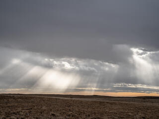 sun breaks through clouds over grasslands in Montana