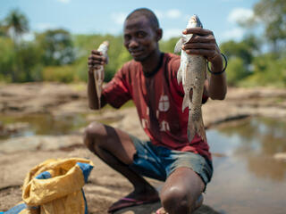 Fisher in Mozambique holds up catch of two fish