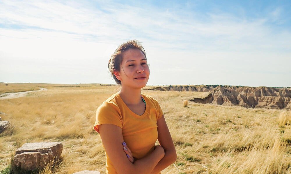 Young woman smiles at camera with rock canyons in distance