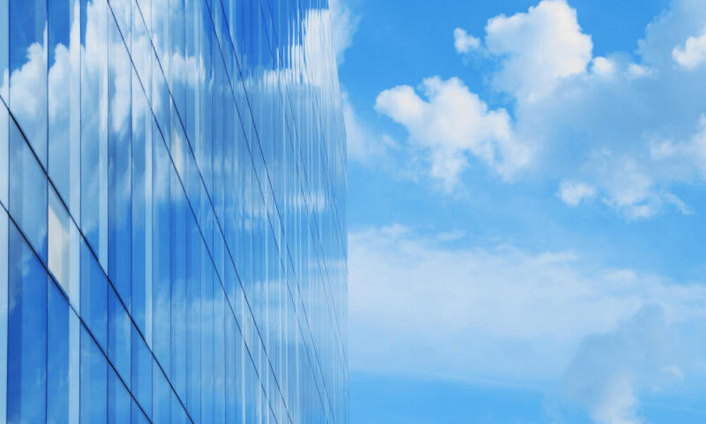 glass office building blue sky and clouds