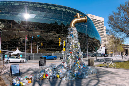 A sculpture of plastic bottles is shaped like a tap and stands in front of the building where negotiations on an international plastic treaty took place