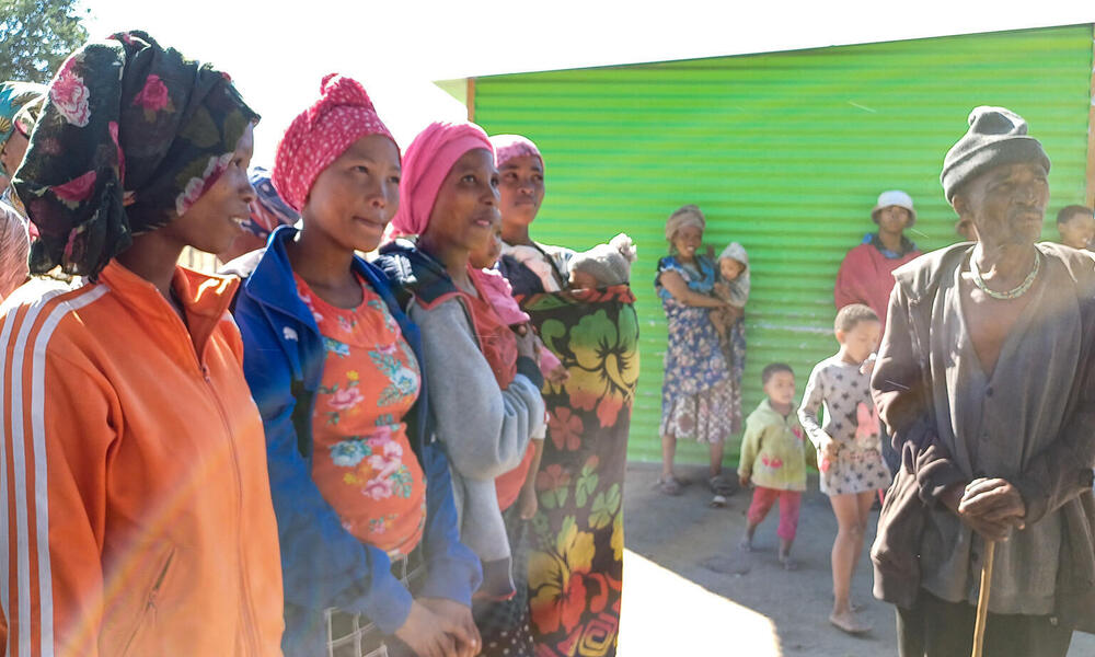 A crowd of African people gathered in front of a green door