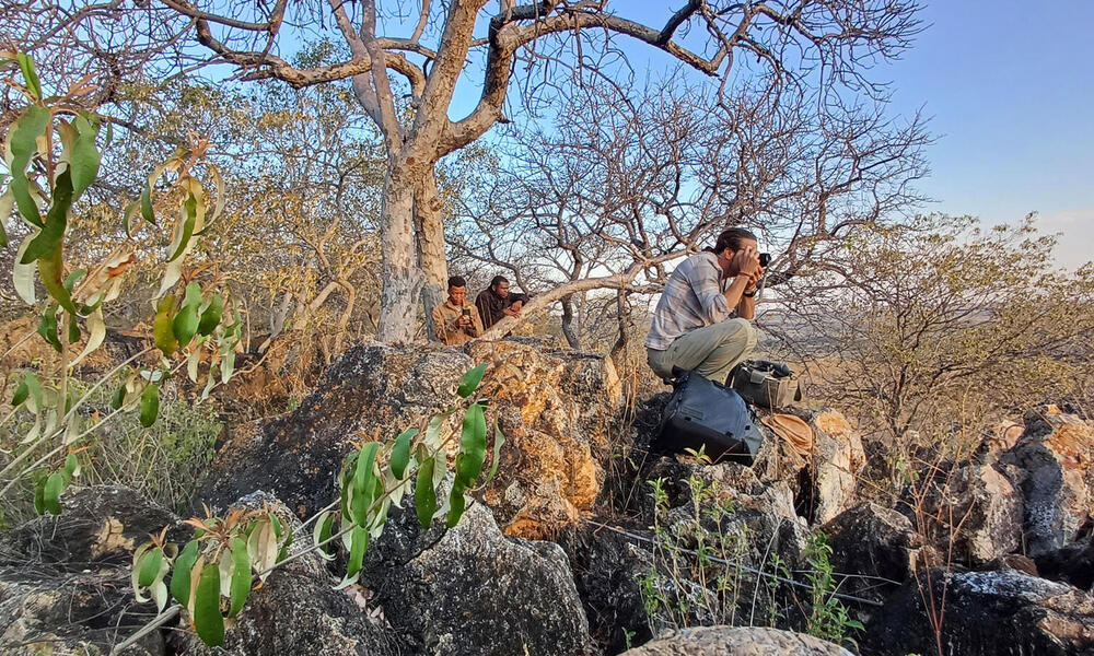 Man crouching on rocks taking photos