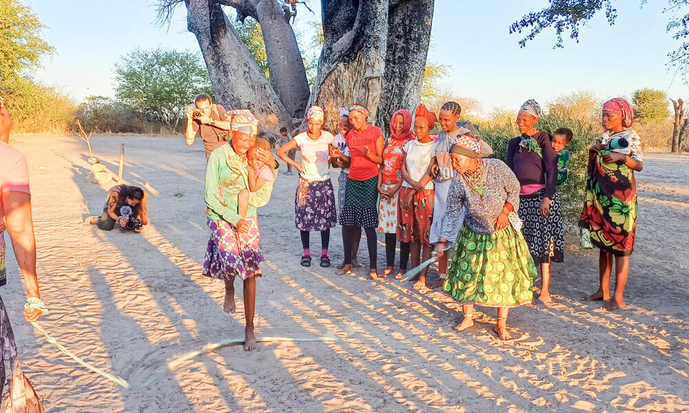 African women jumping rope in sand