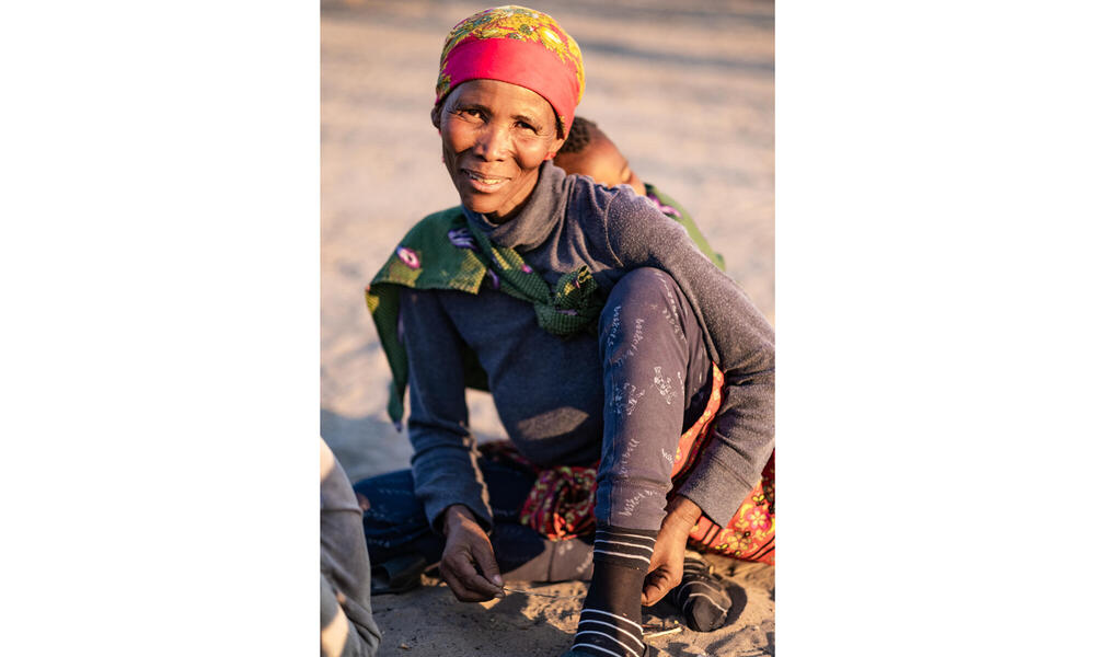 A kneeling woman in headscarf smiles at camera