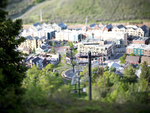 Houses and a ski lift set in a green forested area.