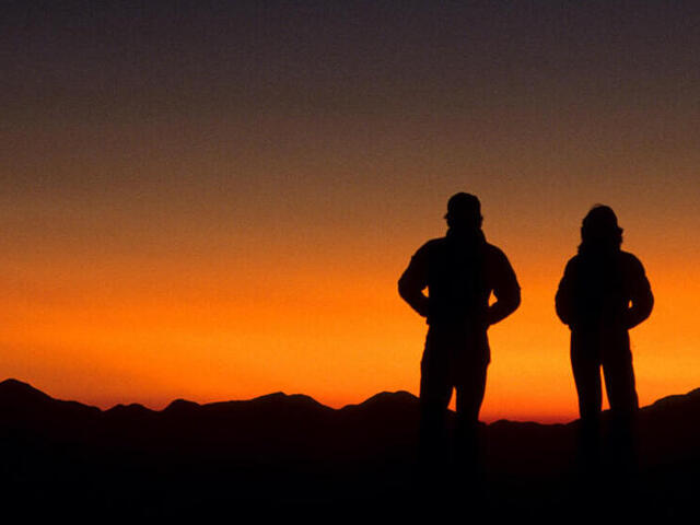 Two hikers silhouetted at sunset, Austrian camp, Dhampus. Annapurna Area, Nepal.