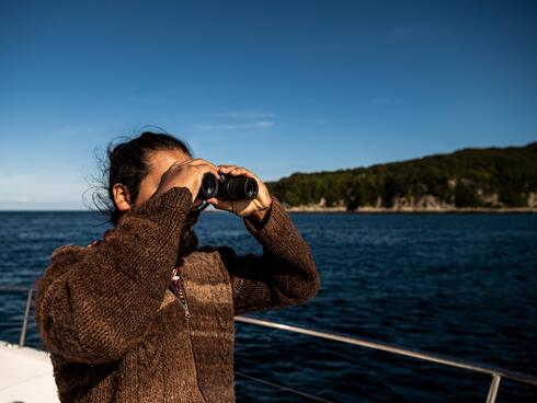 Patricio Colivoro, a Huilliche leader, looks through binoculars to see the wildlife off the coast of Guafo Island