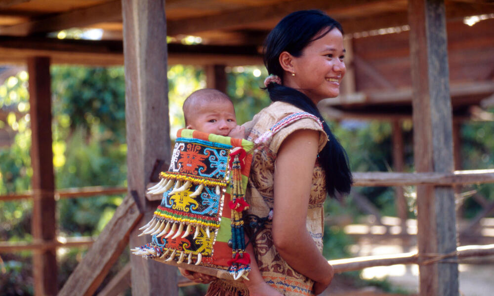 A Kenyah Dayak mother carrying her baby in a traditional hand made carrier