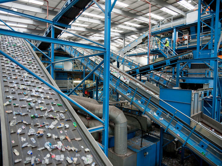 A series of blue and gray conveyor belts moves plastics along at a recycling plant