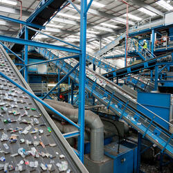 A series of blue and gray conveyor belts moves plastics along at a recycling plant