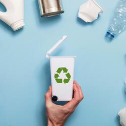 A semi circle of plastics surround a tiny recycling bin on a blue background