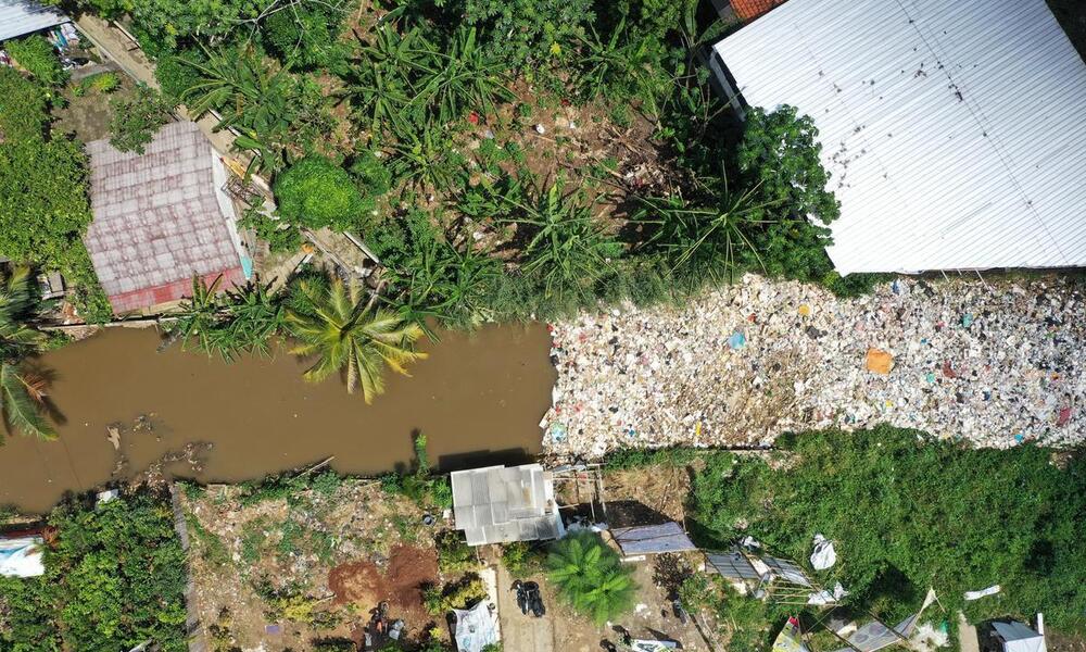 Aerial view of plastics clogging a river between homes in Indonesia