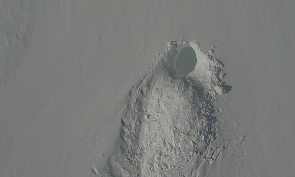 Image of an empty polar bear den in a snowy landscape