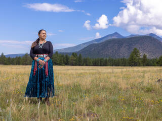 Clara Pratte, in traditional dress, standing in front of mountains 